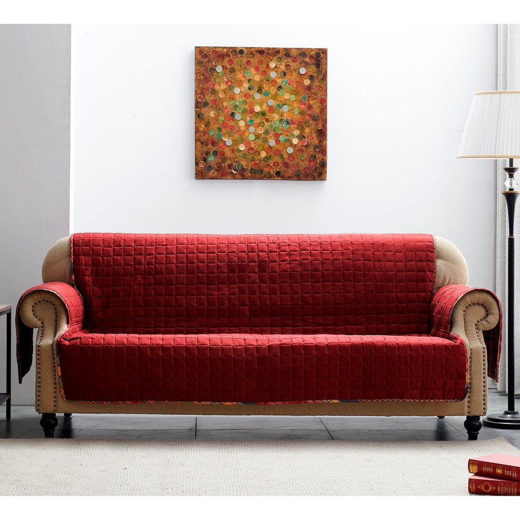Red quilted furniture protector on sofa with wall art