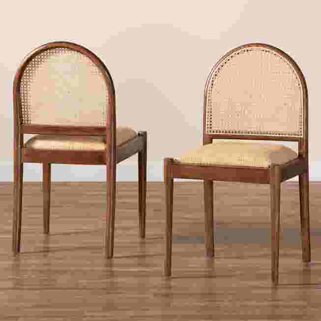 Two dining chairs with natural rattan backs and wooden frames on a wooden floor.