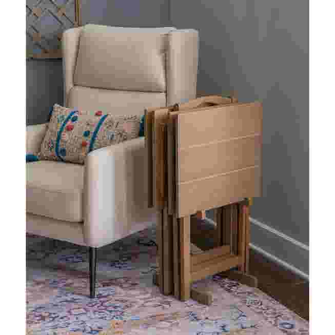 Stacked wooden tray tables next to a white armchair