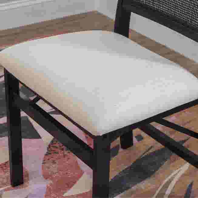Close-up of the seat of a black folding chair with a light-colored cushion.