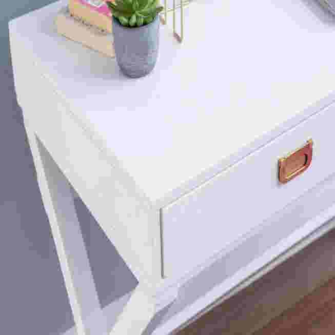 Close-up of a white writing desk with a drawer and a small plant