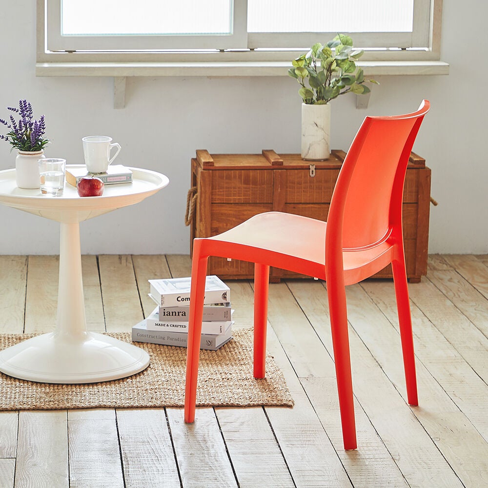 Red-orange molded outdoor dining chair at a patio table