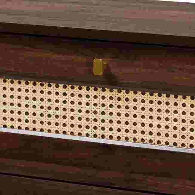 A close-up of the rattan drawer front and the handle of a dark wood chest.