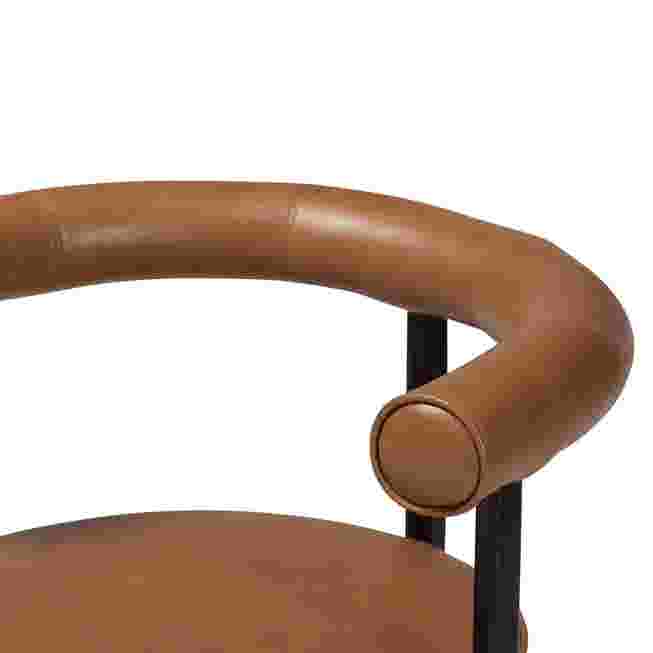 Close-up of the brown leather armrest of the Delacruz swivel dining chair.