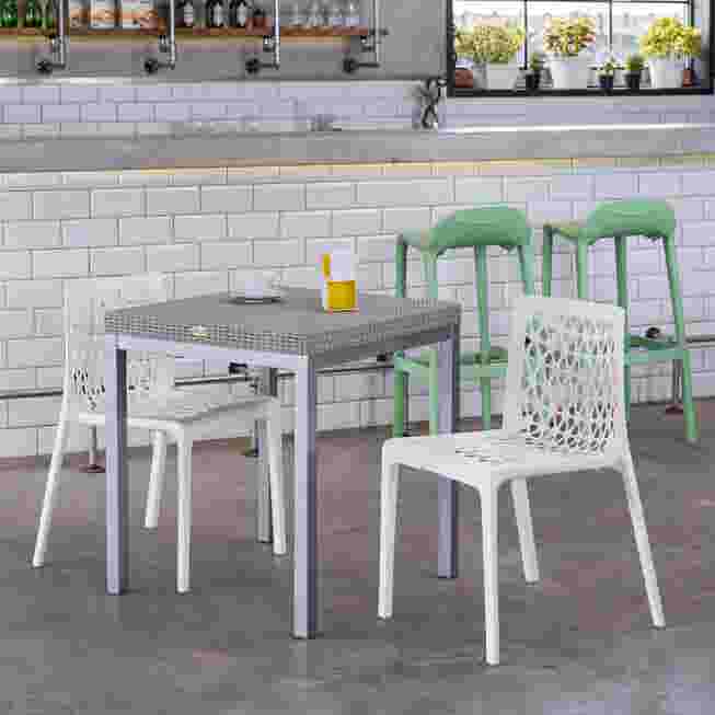 A dining set with white and green Milan chairs around a table in a modern kitchen.
