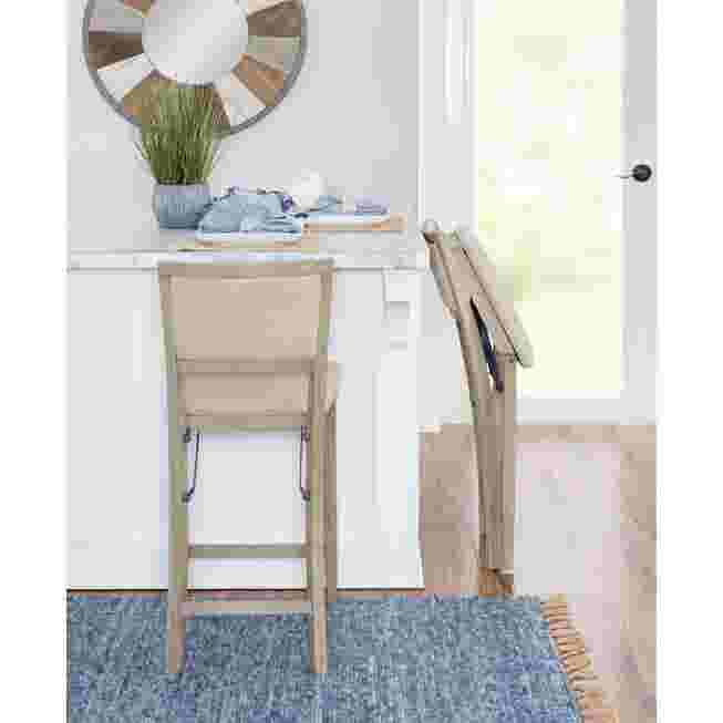 Grey wash folding counter stool with one stool folded against a counter