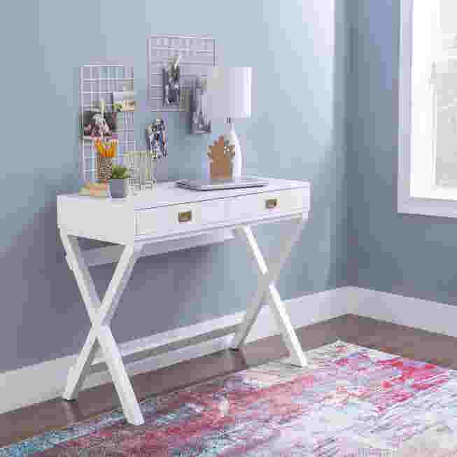 White writing desk in a room with a lamp and various accessories