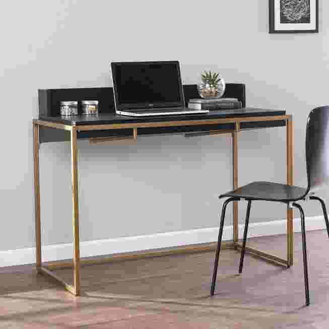 Black desk with gold legs and a laptop on it