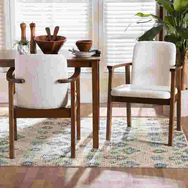 Two white upholstered armchairs with dark wood frames in a dining setting