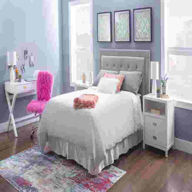 White writing desk in a bedroom with a bed and a pink chair