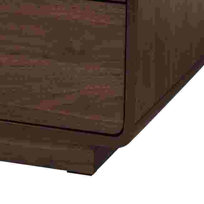 A close-up of the corner and base of a dark wood chest.
